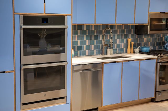 Front view of a blue kitchen with a GE double wall oven