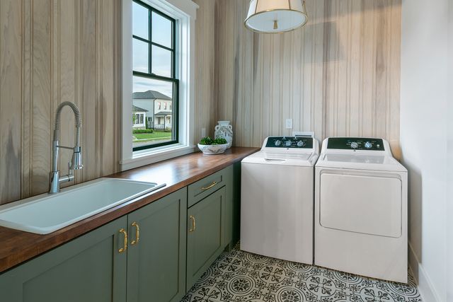 front view of a compact laundry room with light blue cabinets and a white washer and dryer