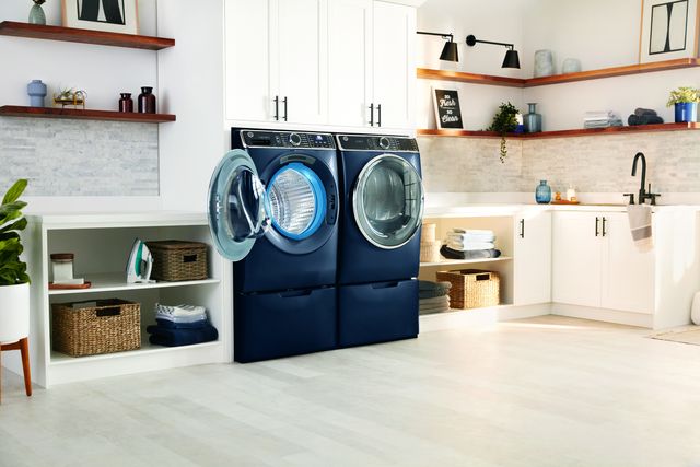 Front view of a GE blue washer and dryer in a modern white laundry room.