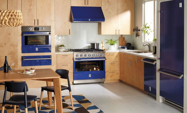 front view of a modern kitchen with blue hestan appliances including a wall oven, range, and over the range hood