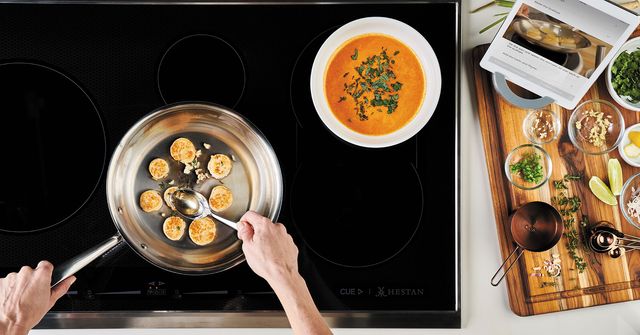 Top view of two arms cooking scallops on a hestan cooktop