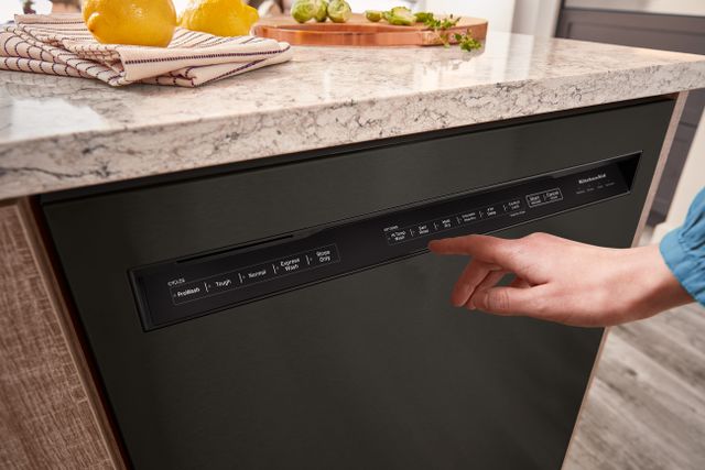 front view of a hand reaching to press a button on a KitchenAid black front control dishwasher