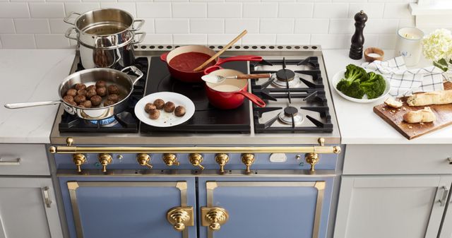 standing view of a la cornue range with spaghetti, meatballs, and sauce cooking in pots and pans across the top of the range