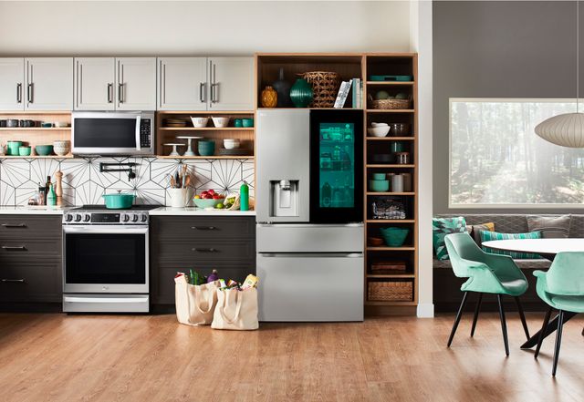 front view of a modern kitchen with grey and beige cabinets, a stainless steel LG instaview refrigerator, and various teal kitchen decor
