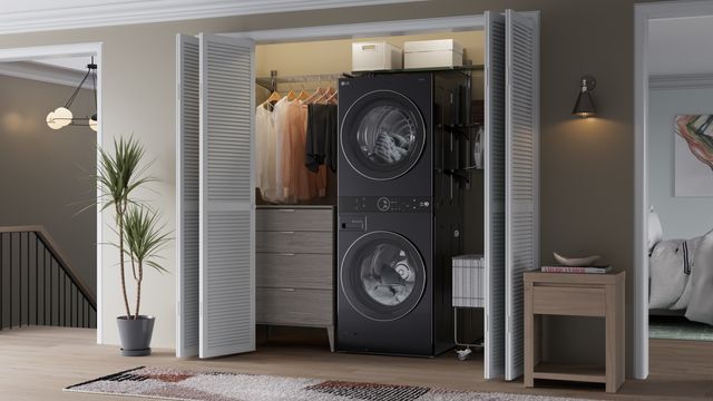Front view of a black LG WashTower in a laundry closet opened in a modern bedroom space