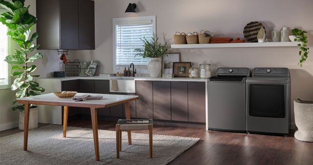 Front view of a modern laundry room with a sink and cabinetry with a grey LG washer and dryer.