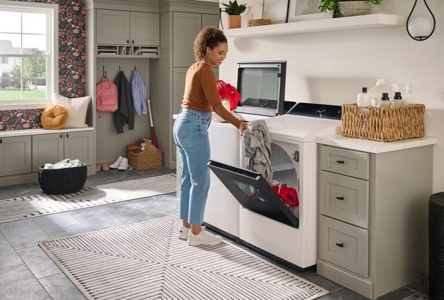 View of a woman moving clothes from her LG top load washer to the dryer