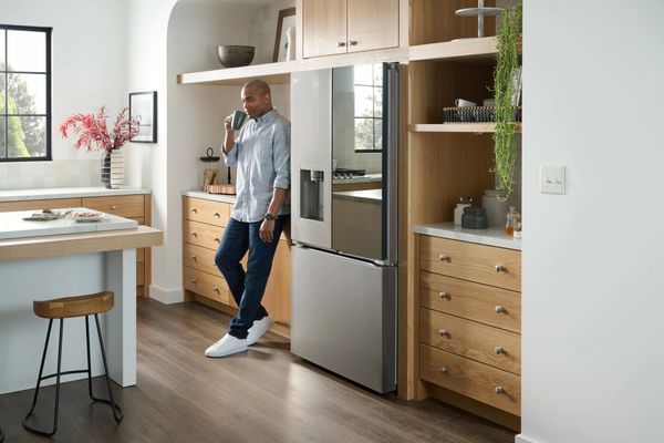 Man Drinking Coffee Next to a Counter Depth Refrigerator