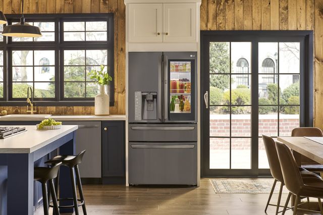 front view of an LG stainless steel instaview frefrigerator with exterior water dispenser in a modern rustic kitchen with large windows