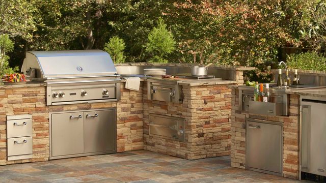 front view of a built in grill with various outdoor kitchen appliances around it