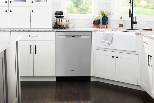 front view of a modern kitchen with white cabinetry and a stainless steel maytag dishwasher