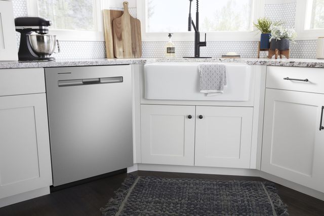 front view of a stainless steel maytag dishwasher built into white cabinetry