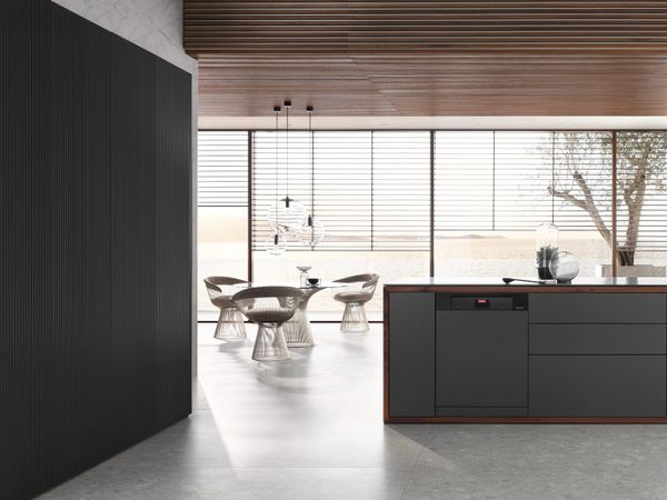 A black panel ready Miele dishwasher in a kitchen with matching black panels