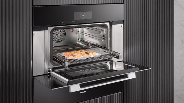 Front view of an opened Miele steam oven with fish being cooked inside