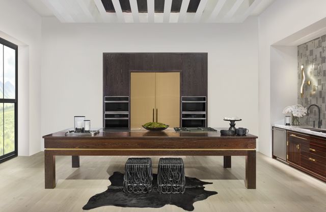 Front view of a modern kitchen with a Monogram panel ready refrigerator between two double wall ovens