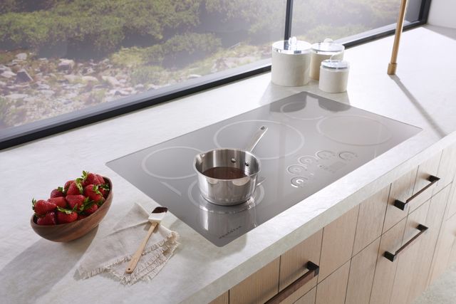 Front view of a modern kitchen with a sleek silver Monogram induction cooktop