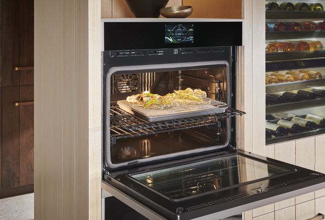 front view of a Monogram wall oven open with a dish of food cooking inside