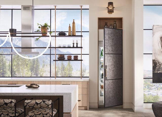 Front view of a modern kitchen with large windows and an integrated Monogram column refrigerator