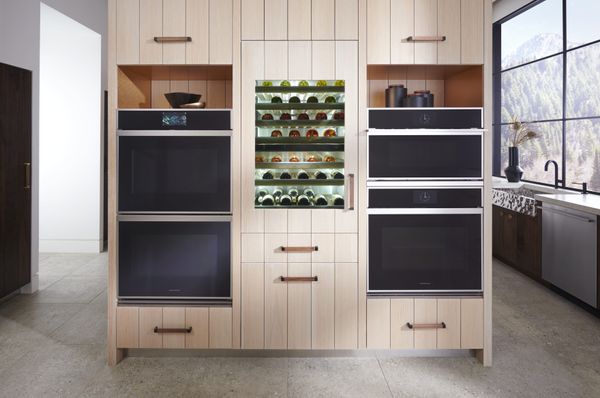 Monogram ovens and wine cooler installed in a wall of light panel wood