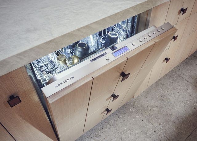 Close view of a slightly opened Monogram dishwasher with an inside a LED light and clean glassware inside.