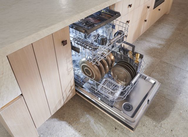 standing of a modern countertop with an opened monogram dishwasher full of clean silverware and glassware