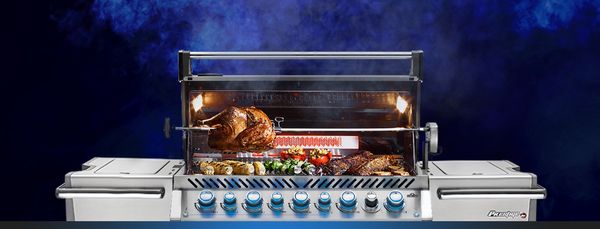 Napoleon grill with open hood and food sizzling atop the grill