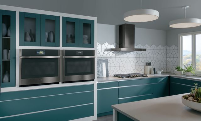 Front view of a modern kitchen with an aqua and white color scheme and two GE Profile wall ovens.