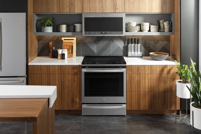 Front view of a modern kitchen with a GE Profile induction range with front controls and over the range microwave