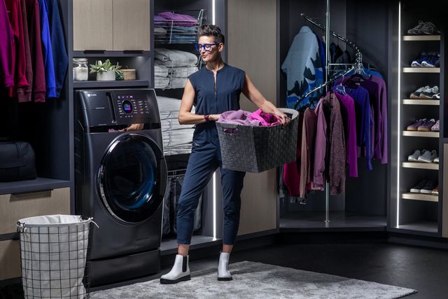front view of a woman with a laundry basket in a large walk in closet with a ge profile washer dryer combo