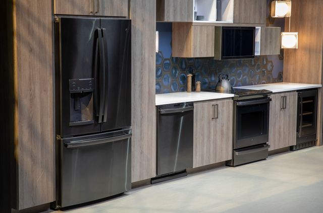 left angled view of a modern kitchen wall with wooden cabinetry and black stainless steel ge profile appliances