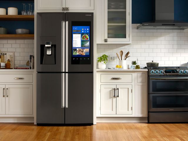 front view of a samsung familyhub black stainless steel refrigerator built into white cabinetry in a modern kitchen