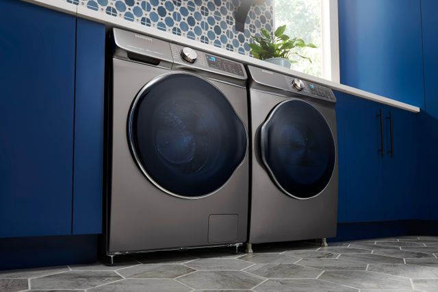 Low view of a modern laundry room with blue cabinetry and a silver Samsung washer and dryer.