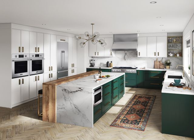 front view of a modern luxurious kitchen with a white marble island, white cabinets, green cabinets under the island, and stainless steel signature kitchen suite appliances throughout