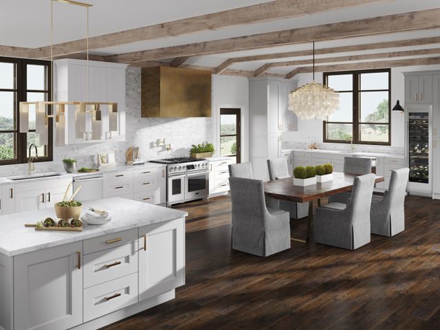 front view of a large, open, luxury white kitchen with Signature Kitchen Suite appliances and gold accents
