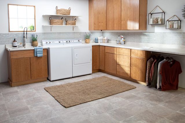 view of a modern laundry room with white walls and light wooden cabinetry. Built into the cabinetry is the Speed Queen TC5 washer and DR7 dryer.