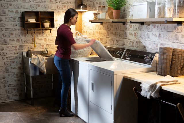 front view of a modern laundry room with a woman loading her speed queen washer
