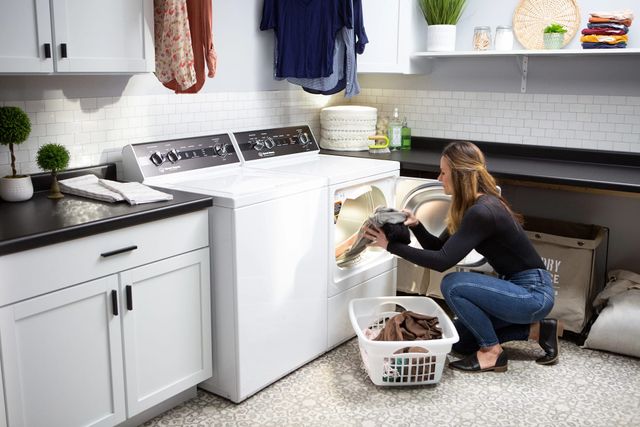 view of a woman loading her Speed Queen dryer in a modern laundry room