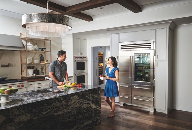 Front view of a modern luxury kitchen with a Sub-Zero PRO Series refrigerator and a couple cooking 