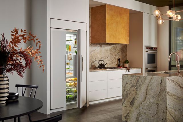 Front view of a modern kitchen with a Sub-Zero panel ready refrigerator slightly opened