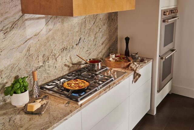 Front view of a modern cookspace with a marble reflective backsplash