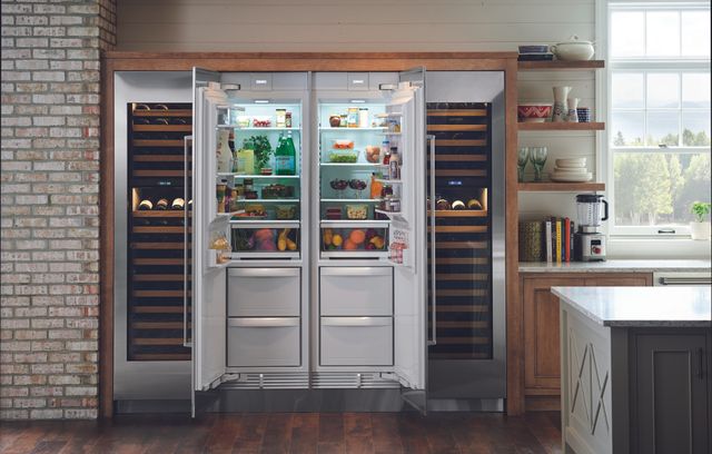 Front view of a rustic style kitchen with two open Sub-Zero column refrigerators and two column wine coolers around them.