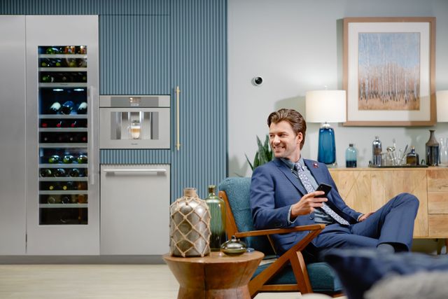 Front view of a man sitting and looking back at his kitchen and Thermador appliances