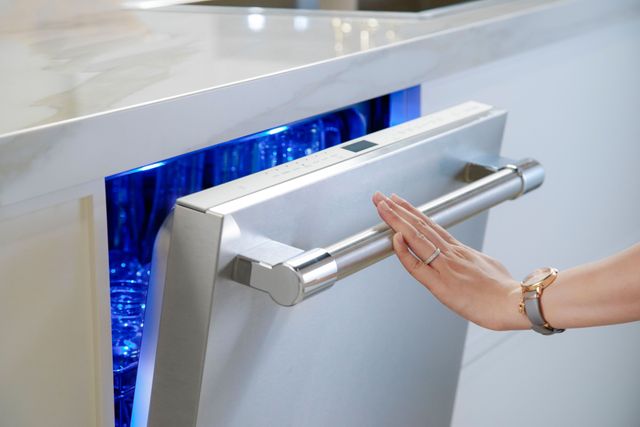 close view of a slightly opened Thermador dishwasher showcasing the blue light inside
