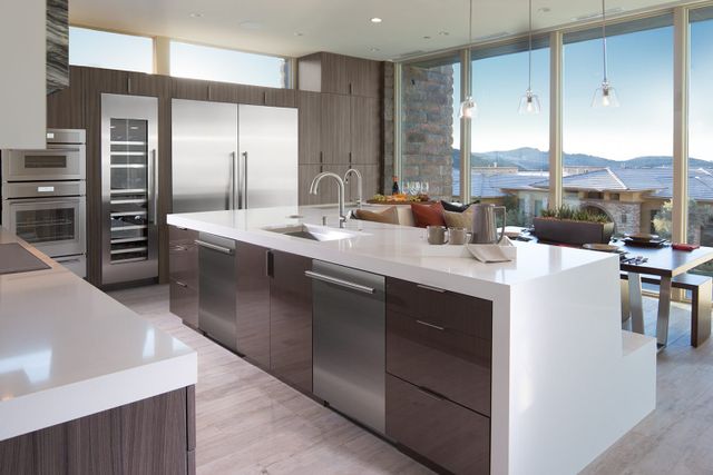 front view of a modern kitchen with stainless steel Thermador appliances including a double oven, wine cooler, refrigerator, trash compactor, and dishwasher