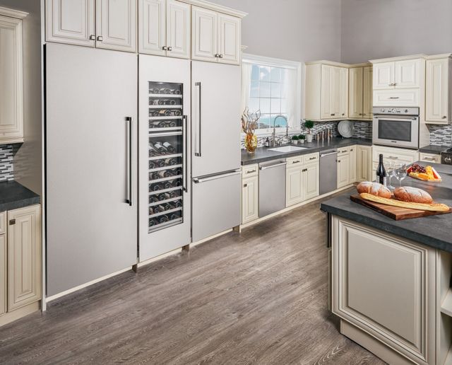 Front view of a modern kitchen with white cabinetry and stainless steel Thermador appliances including two refrigerators and a wine fridge