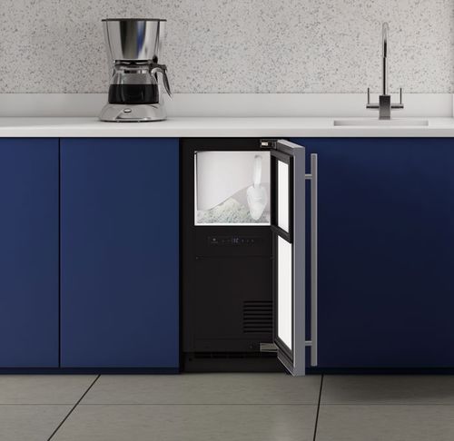 front view of a u-line ice machine in a lower blue kitchen cabinet
