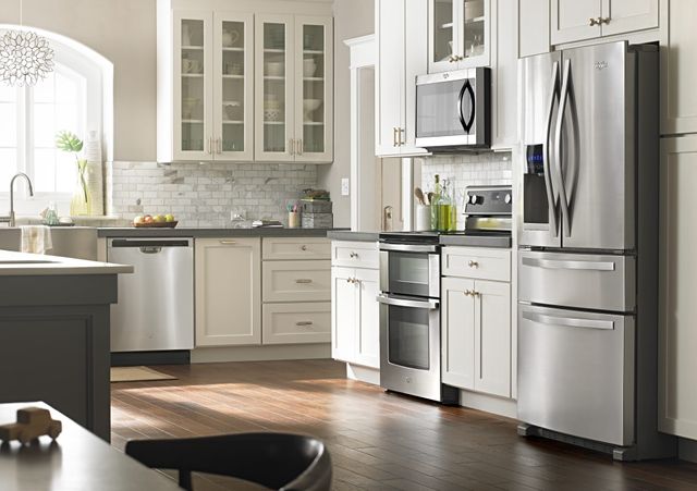 Front view of a modern kitchen with a stainless steel Whirlpool kitchen appliance package.