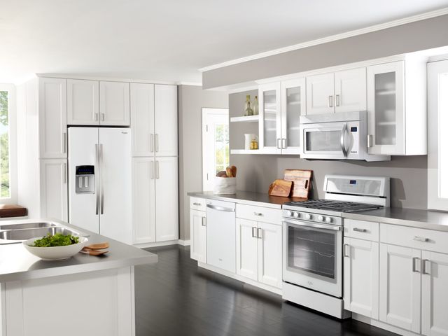 Front view of a modern white kitchen with a white side-by-side Whirlpool refrigerator