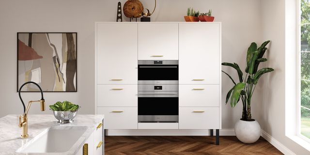 Front view of two Wolf wall ovens built into a modern kitchen wall with white cabinetry.