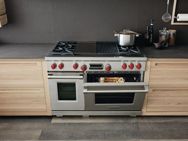 front view of a large 48" Wolf range oven with the oven door slightly opened and a pot on top of the heating elements